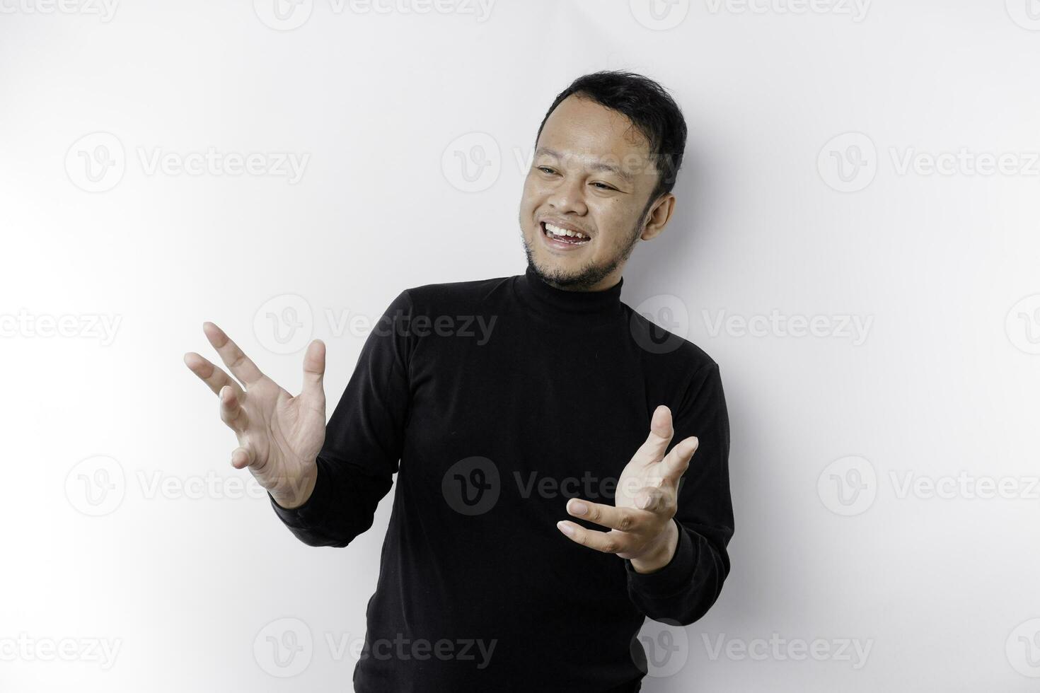 Young Asian man wearing black t-shirt presenting an idea while looking smiling on isolated white background photo