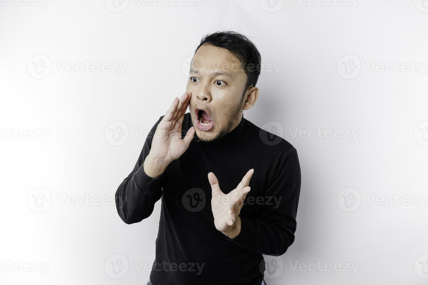 Young handsome man wearing a black shirt shouting and screaming loud with a hand on his mouth. communication concept. photo