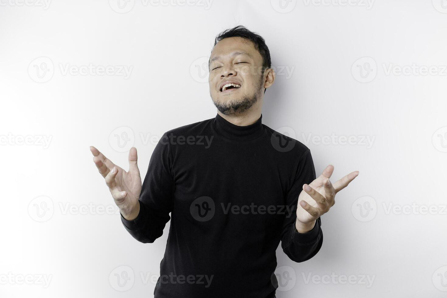 Young Asian man wearing black t-shirt presenting an idea while looking smiling on isolated white background photo