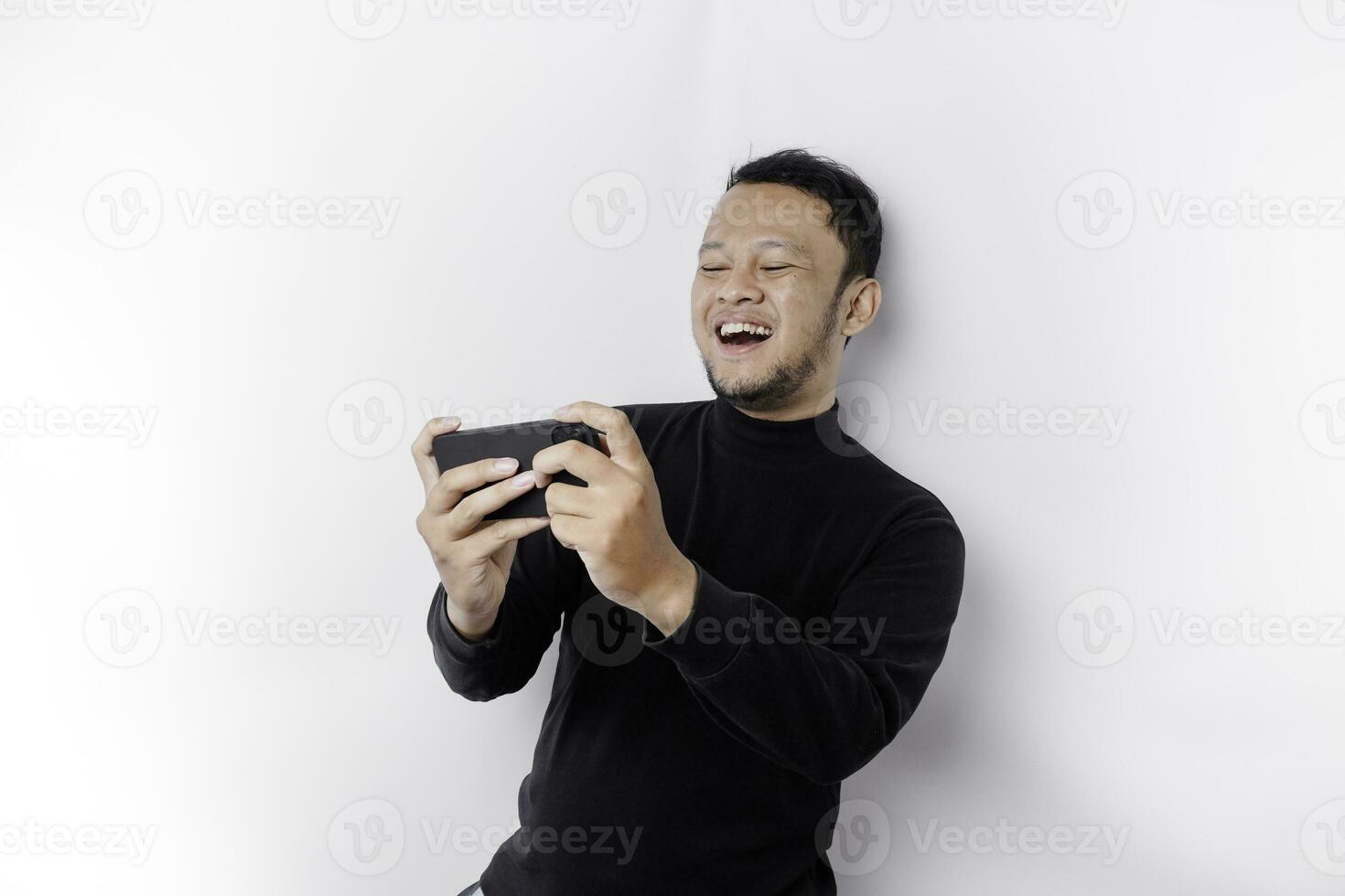 Young Asian man in casual wear is playing games with mobile phone with a white background isolated. photo