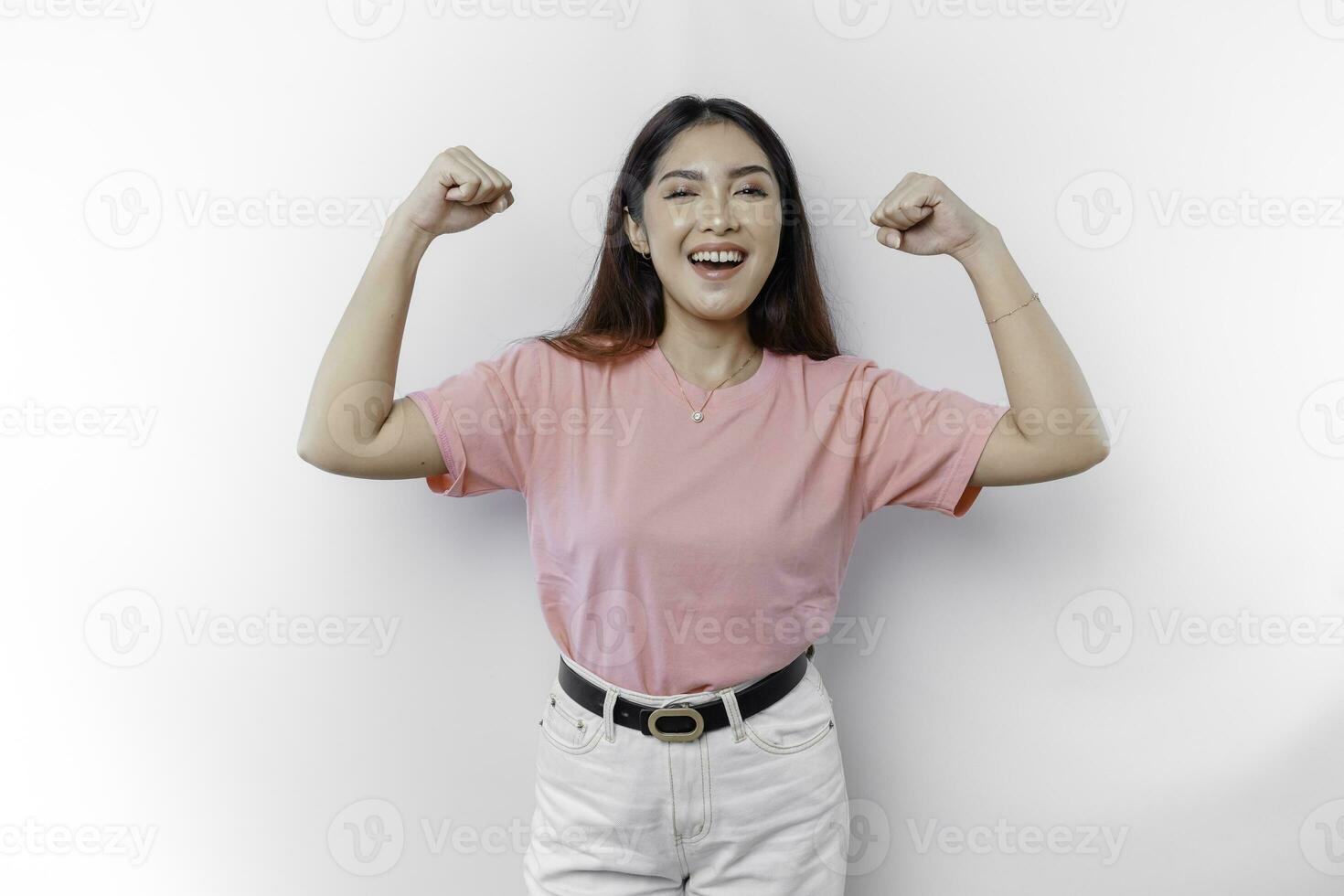 Excited Asian woman wearing a pink t-shirt showing strong gesture by lifting her arms and muscles smiling proudly photo