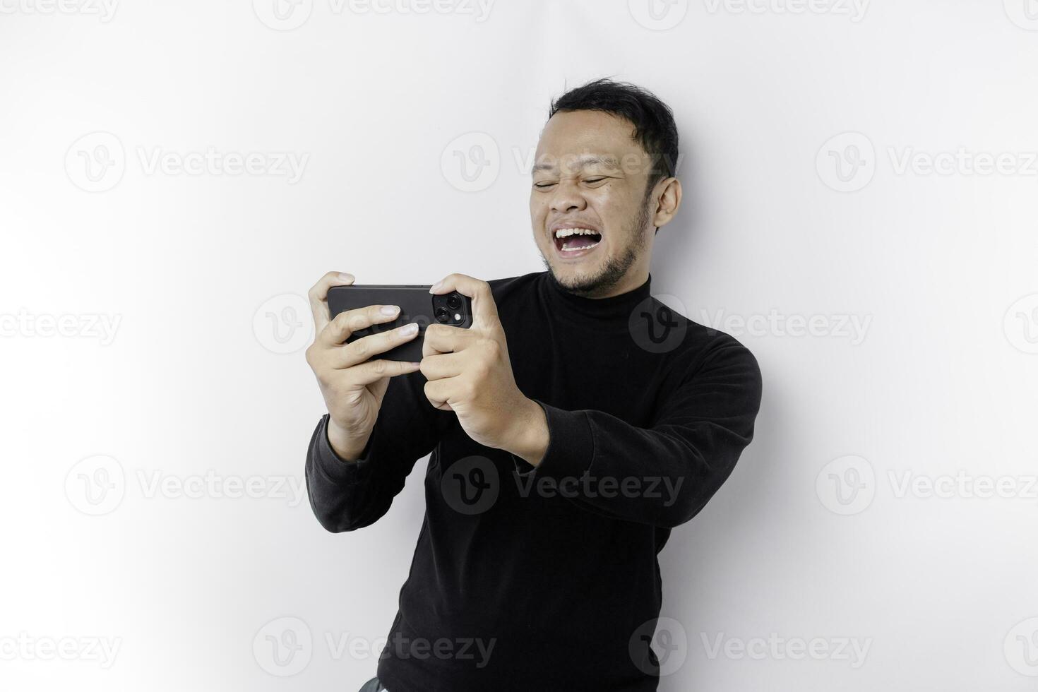 Young Asian man in casual wear is playing games with mobile phone with a white background isolated. photo