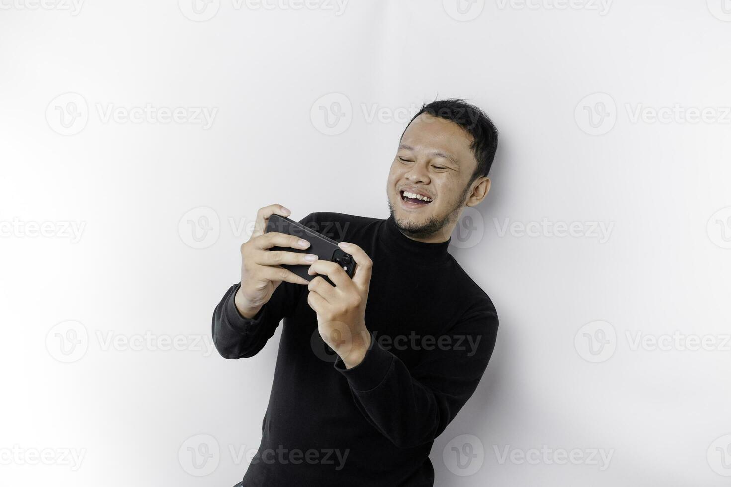 Young Asian man in casual wear is playing games with mobile phone with a white background isolated. photo