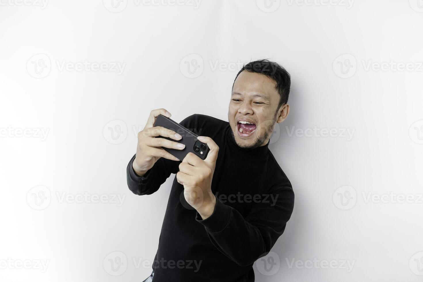 Young Asian man in casual wear is playing games with mobile phone with a white background isolated. photo