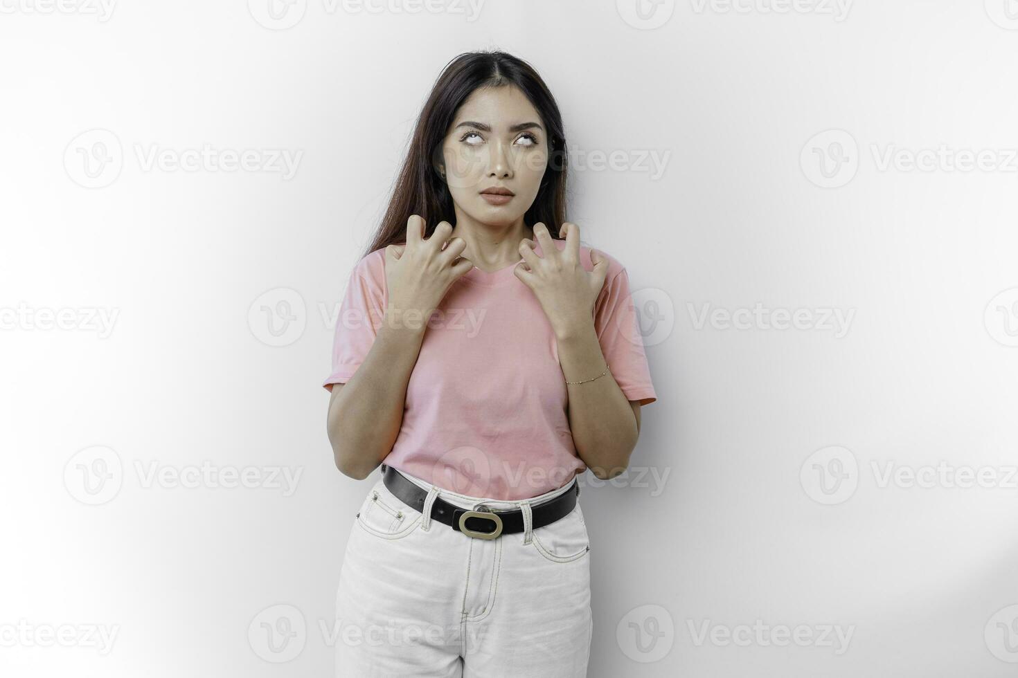 A dissatisfied young Asian woman looks at the camera posing on a white background, disgruntled girl with irritated face expressions show negative attitude concept image photo