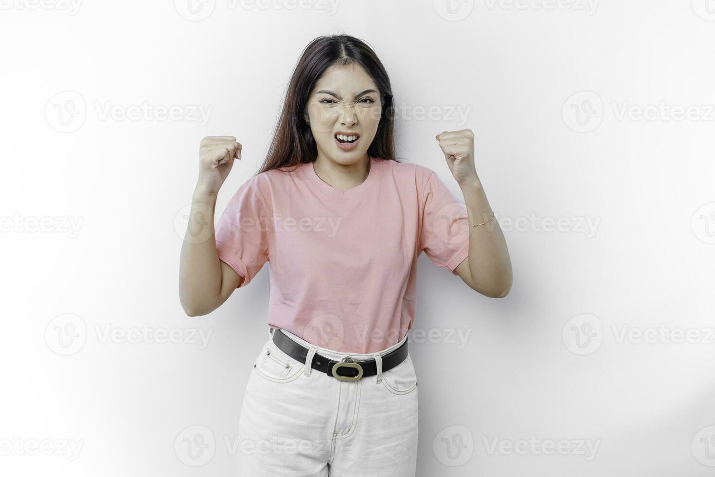 A dissatisfied young Asian woman looks at the camera posing on a white background, disgruntled girl with irritated face expressions show negative attitude concept image photo