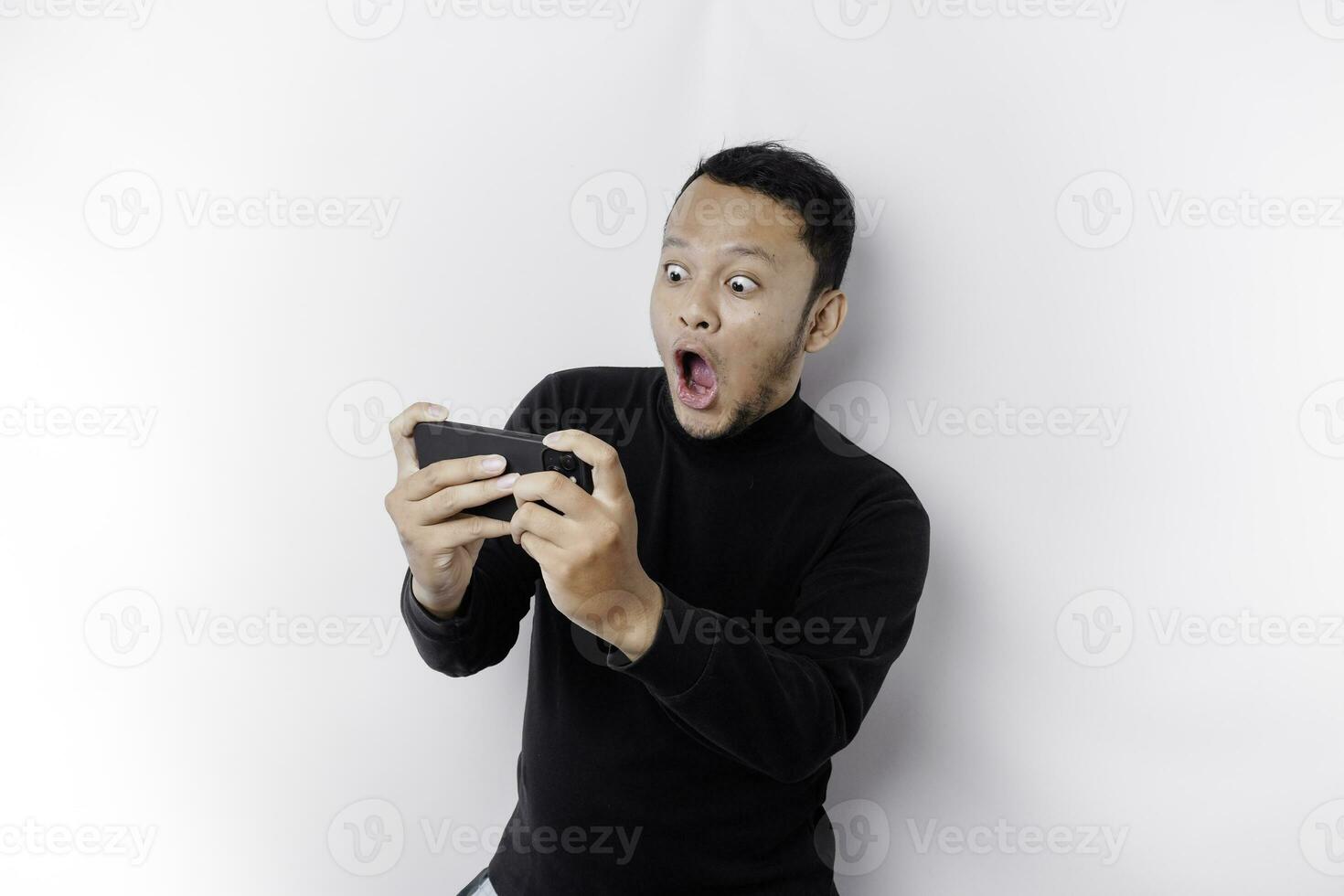 Young Asian man in casual wear is playing games with mobile phone with a white background isolated. photo