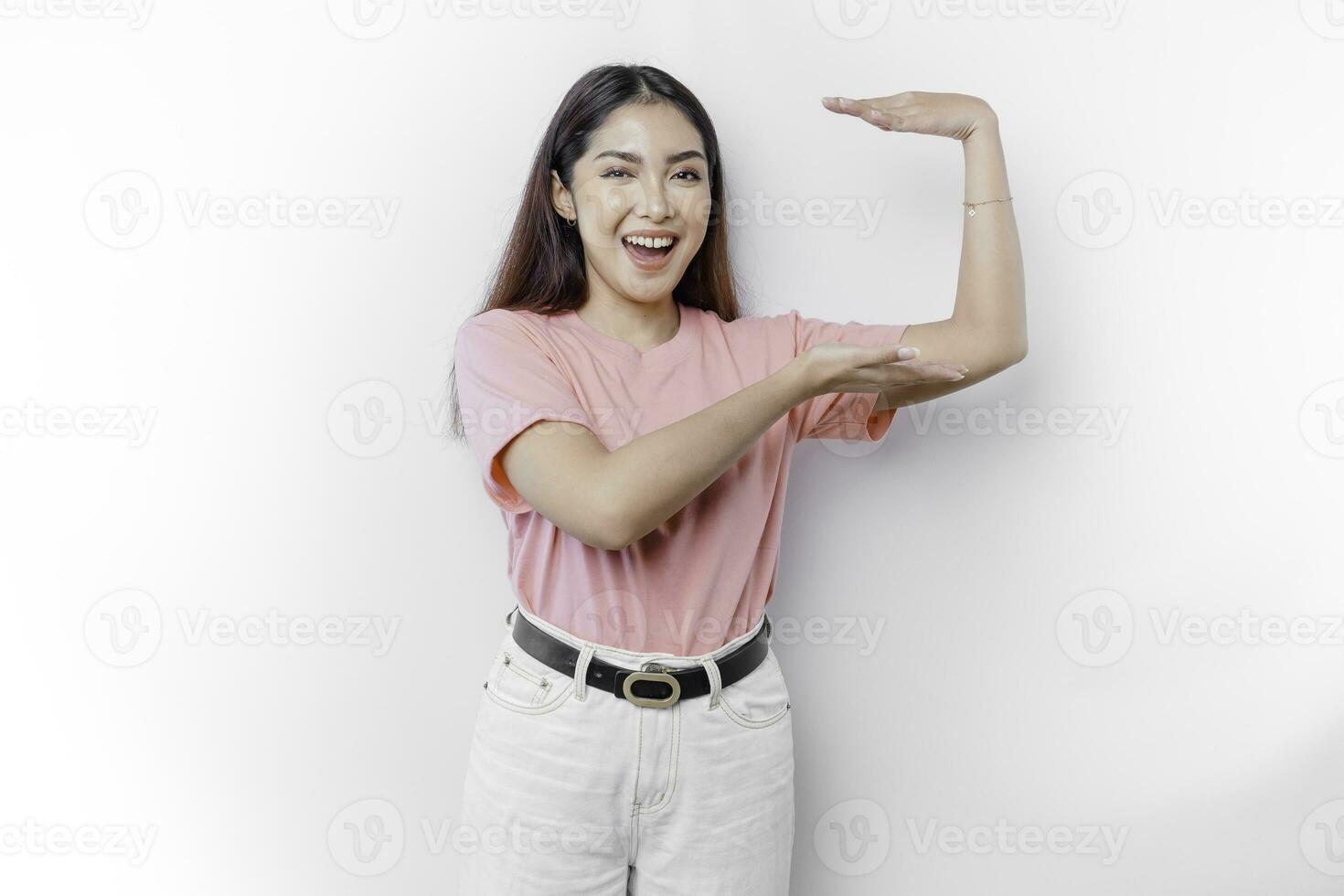Smiling young Asian woman is standing over isolated background holding copy space imaginary on the palm to insert an ad photo