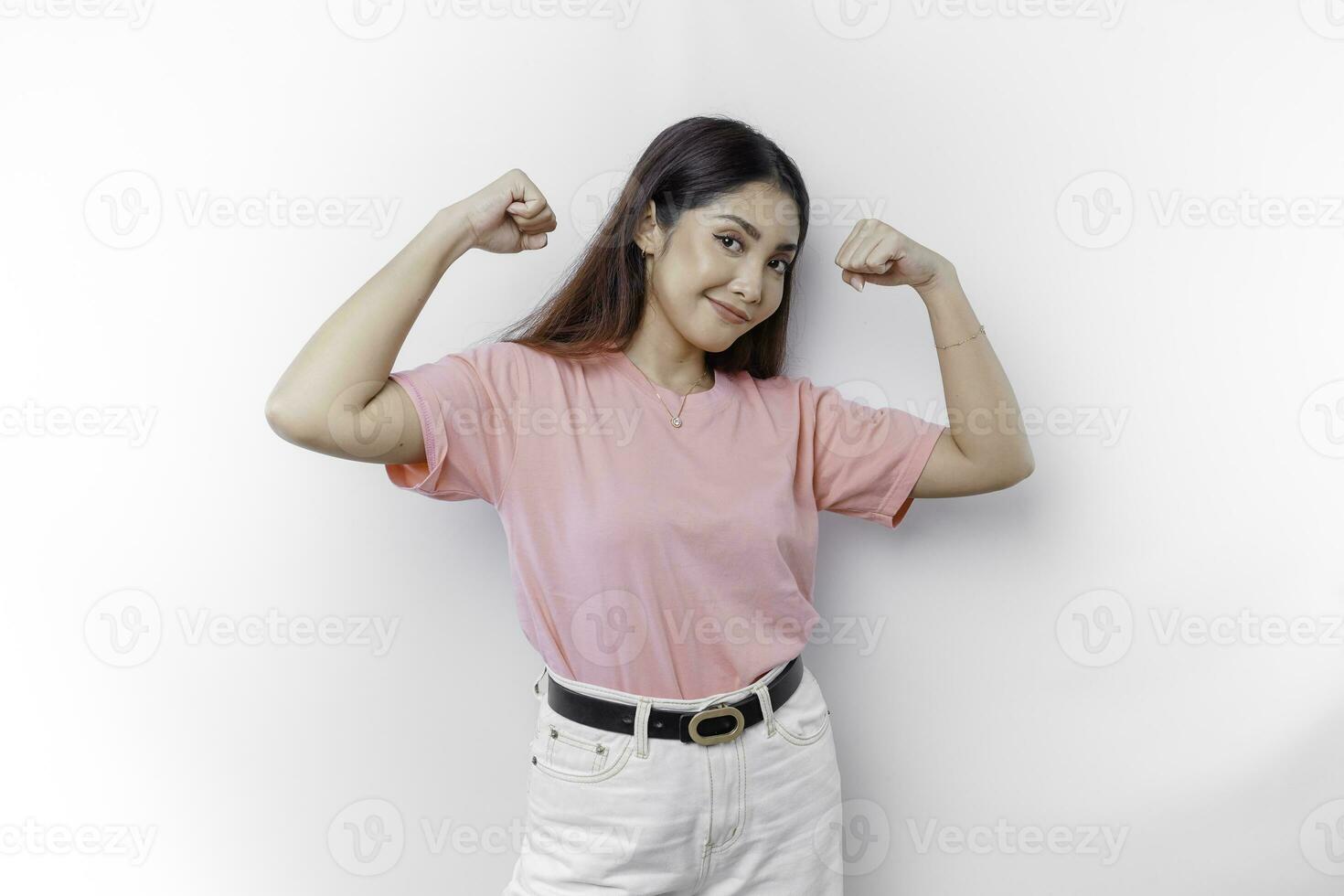 Excited Asian woman wearing a pink t-shirt showing strong gesture by lifting her arms and muscles smiling proudly photo