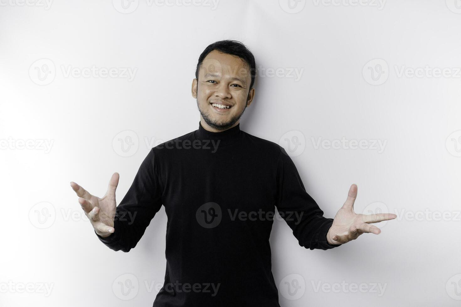 Young Asian man wearing black t-shirt presenting an idea while looking smiling on isolated white background photo