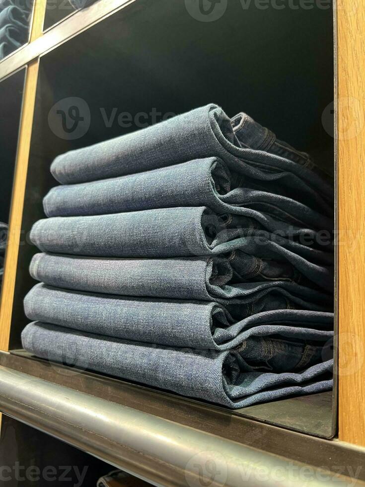 Denim clothes are stacked on a shelf. photo