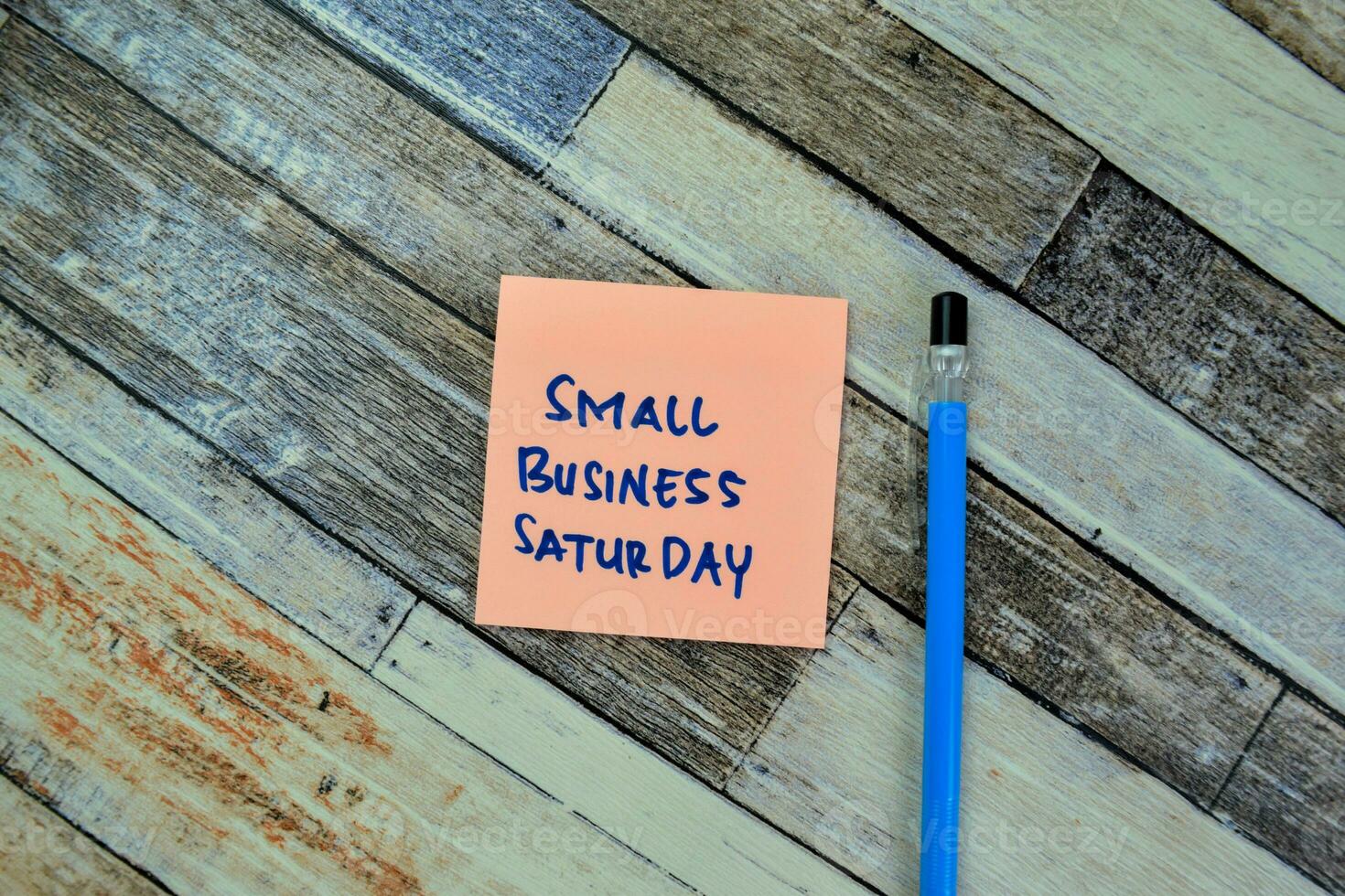 Concept of Small Business Saturday write on sticky notes isolated on Wooden Table. photo