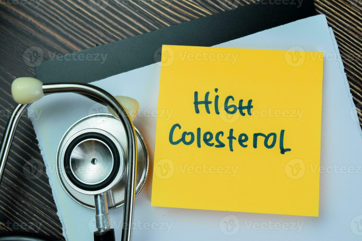 Concept of High Cholesterol write on sticky notes isolated on Wooden Table. photo
