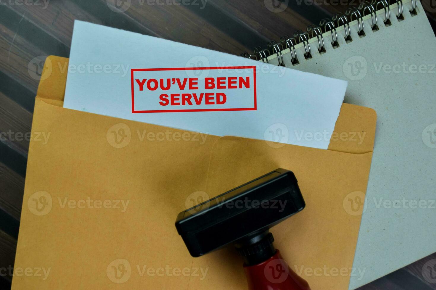 Concept of Red Handle Rubber Stamper and You've been Served text above from brown envelope isolated on on Wooden Table. photo