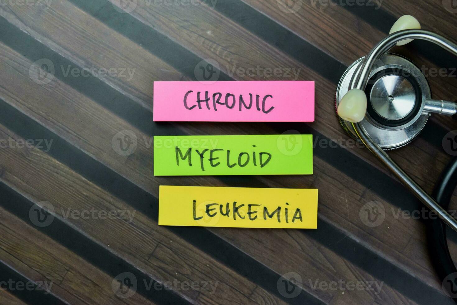 Concept of Chronic Myeloid Leukemia write on sticky notes with stethoscope isolated on Wooden Table. photo