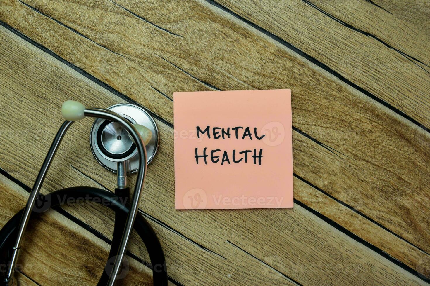 Concept of Mental Health write on sticky notes with stetoshocope isolated on Wooden Table. photo
