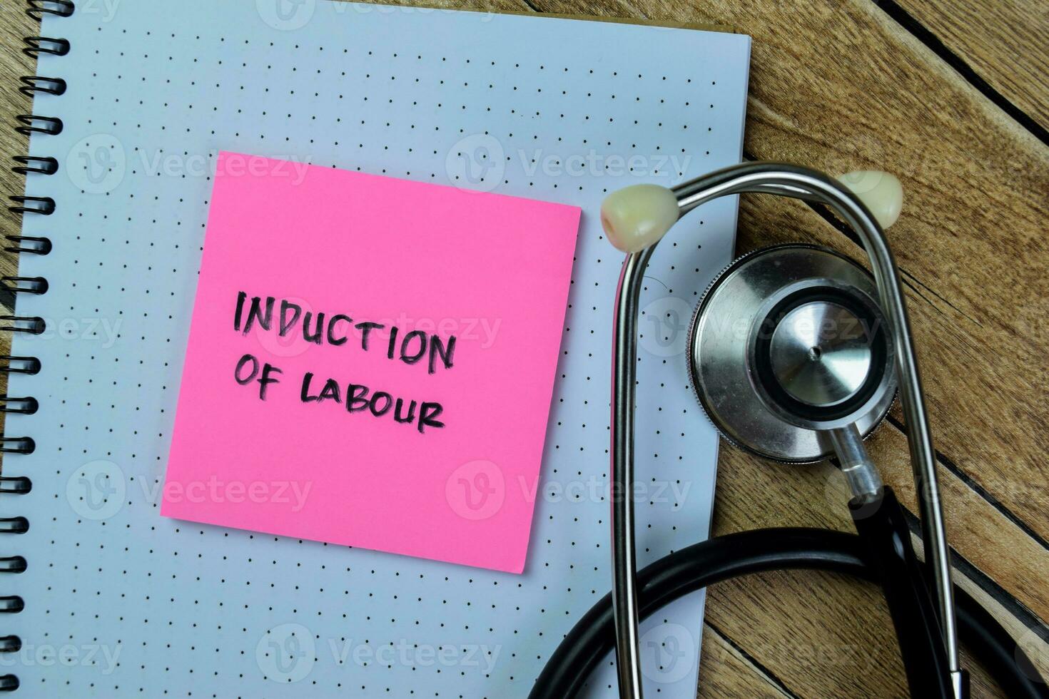 Concept of Induction of Labour write on sticky notes with stethoscope isolated on Wooden Table. photo