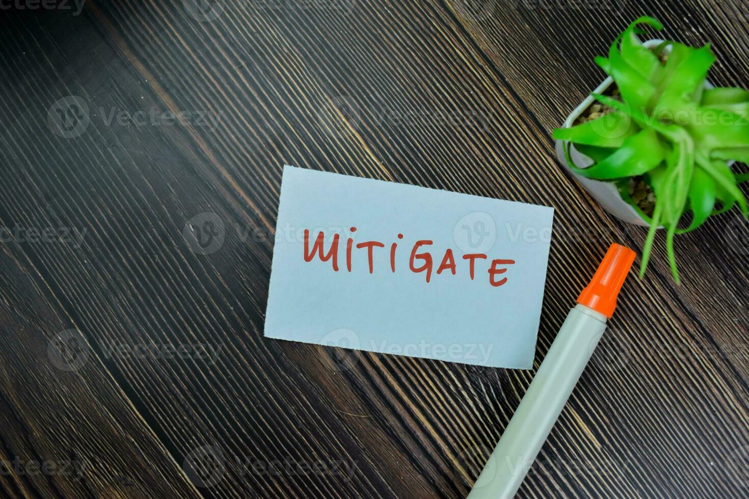 Concept of Mitigate write on sticky notes isolated on Wooden Table. photo