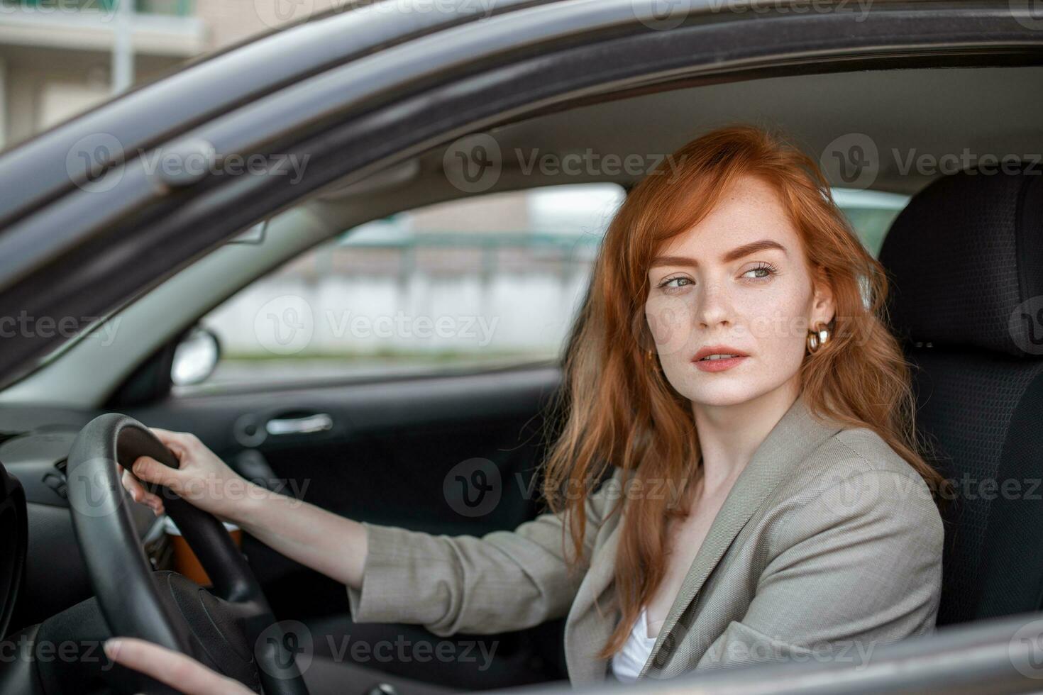 Beautiful young woman driving her new car at sunset. Woman in car. Close up portrait of pleasant looking female with glad positive expression, woman in casual wear driving a car photo