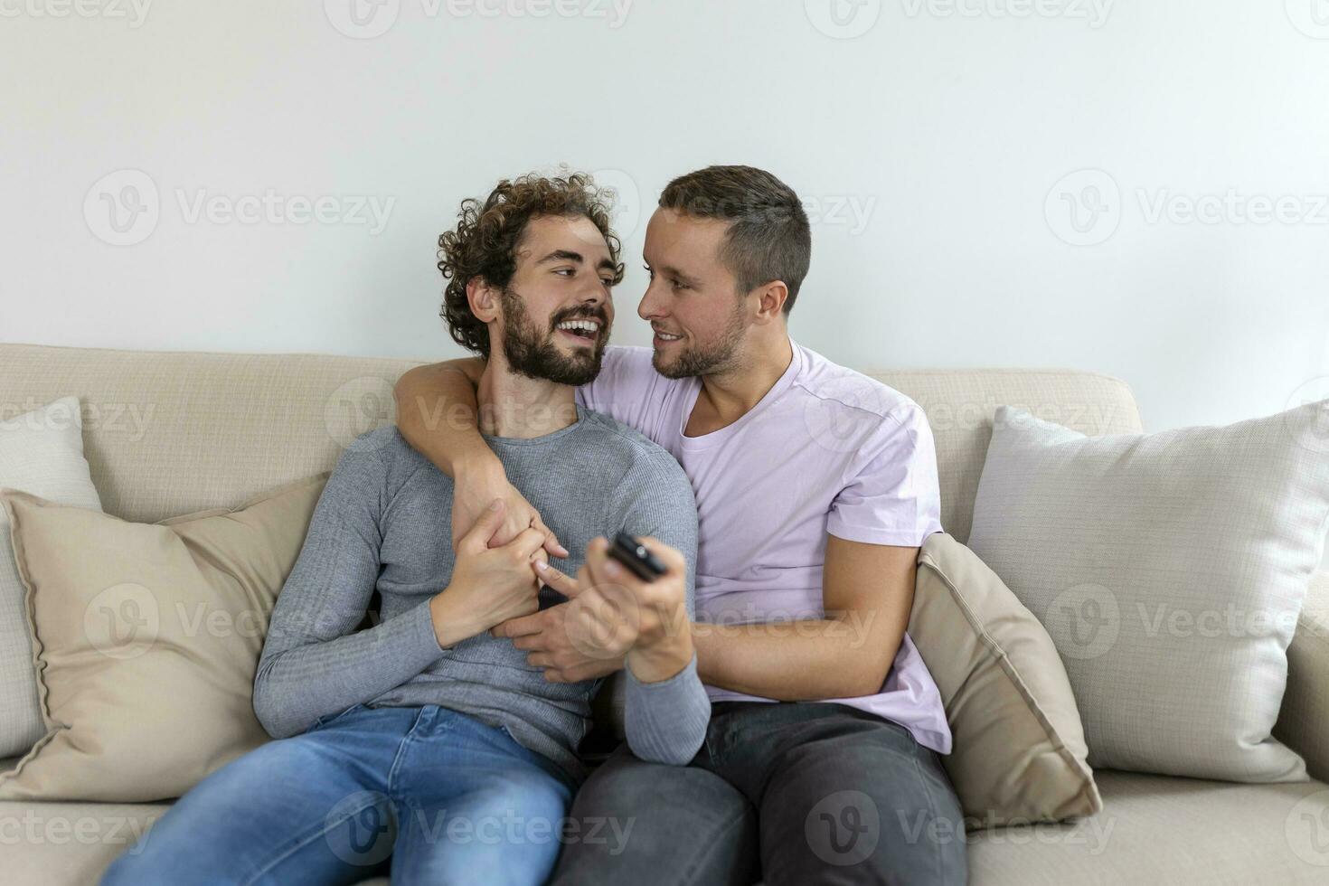 joven homosexual Pareja relajante en sofá en el vivo habitación, abrazando y disfrutando mientras acecho televisión foto