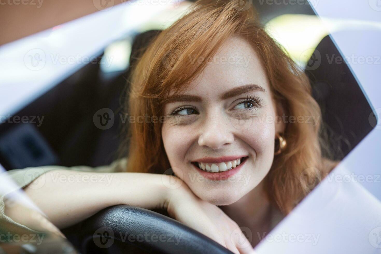 Young Woman Embracing Her New Car. Excited young woman and her new car indoors. Young and cheerful woman enjoying new car hugging steering wheel sitting inside photo