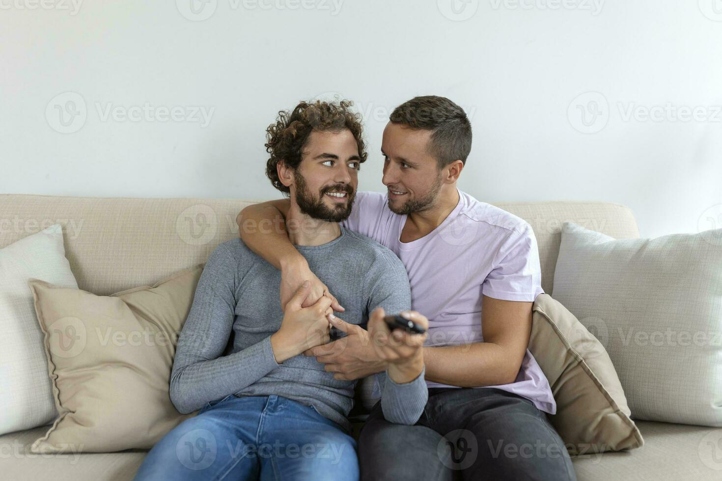 joven homosexual Pareja relajante en sofá en el vivo habitación, abrazando y disfrutando mientras acecho televisión foto