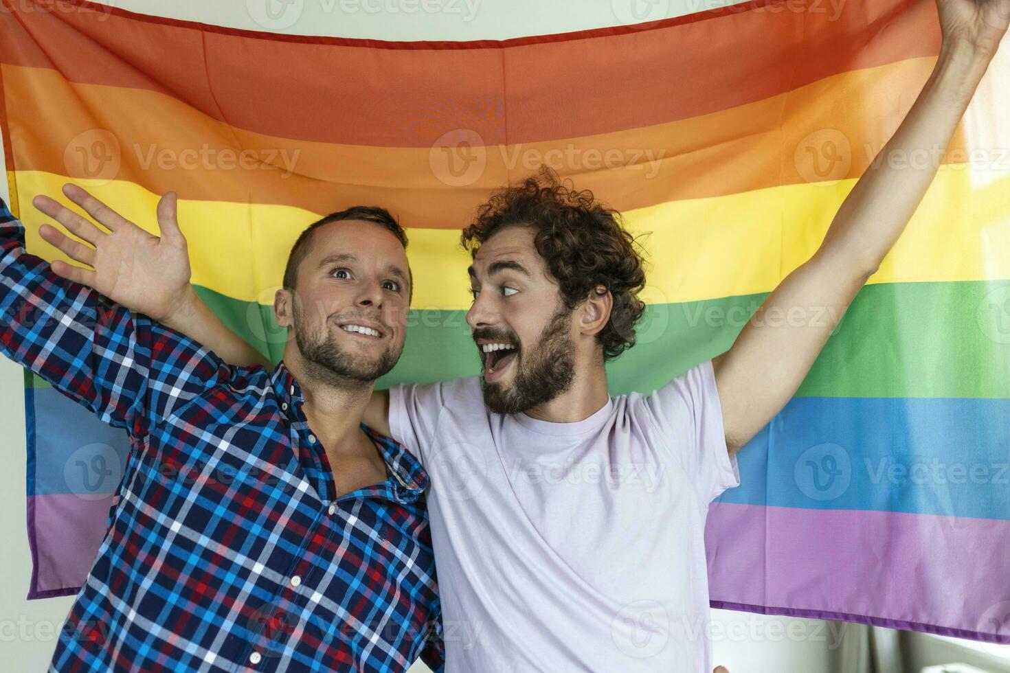 dos joven gay amantes mirando a cada otro afectuosamente. dos joven masculino amantes en pie juntos en contra un orgullo bandera. cariñoso joven gay Pareja compartiendo un romántico momento juntos. foto