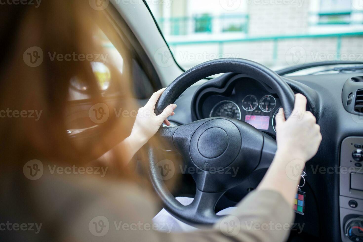 Beautiful smiling young redhead woman behind steering wheel driving car. photo