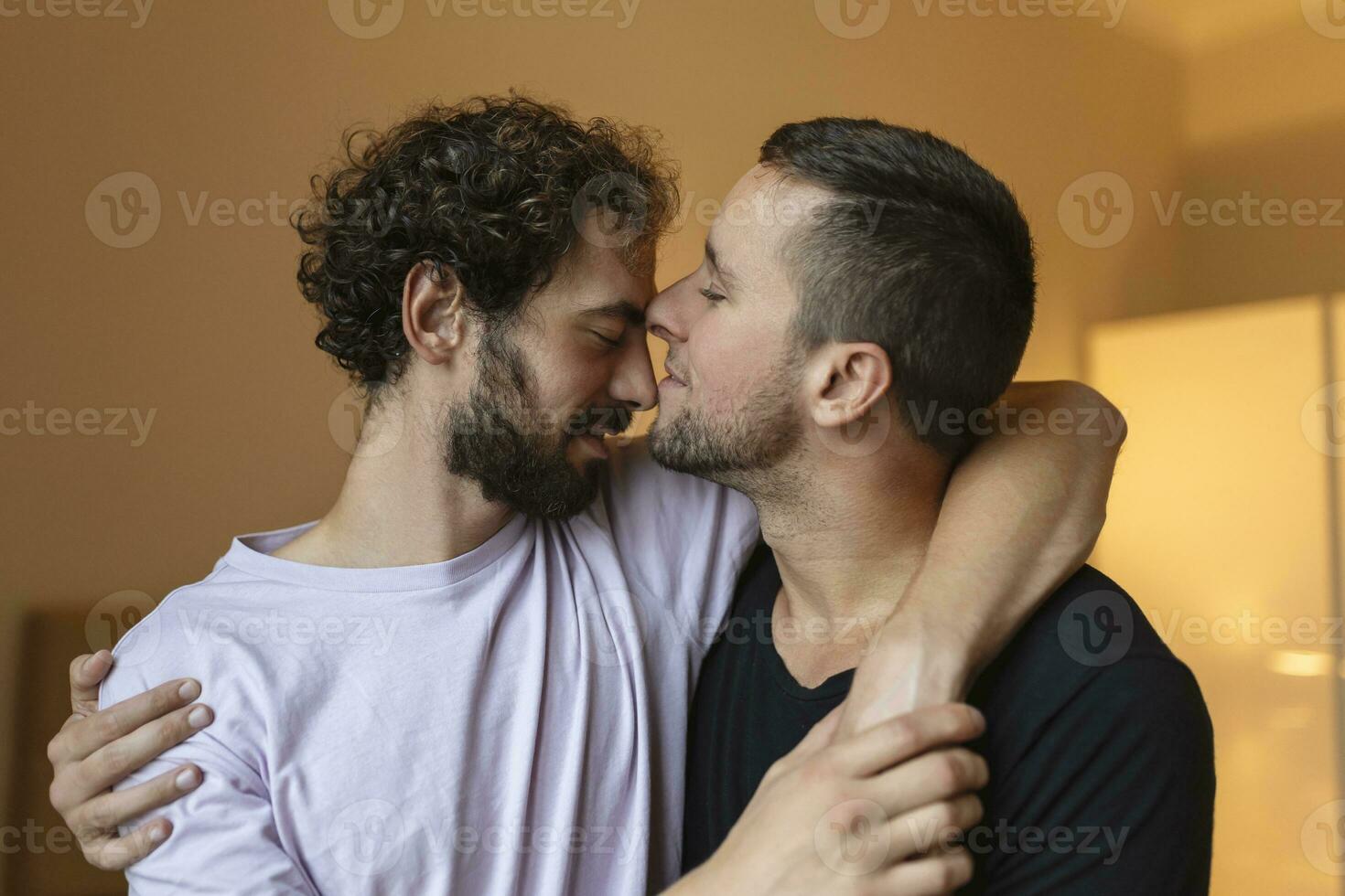 Two young man lgbtq gay couple dating in love hugging enjoying intimate tender sensual moment together kissing with eyes closed photo