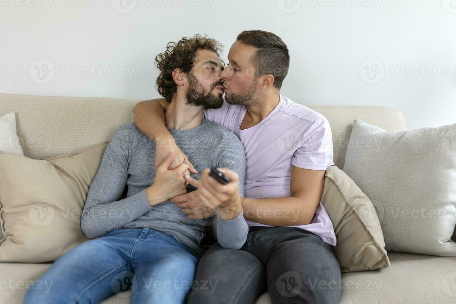 Young homosexual couple relaxing on sofa in the living room, embracing and enjoying while watching TV photo