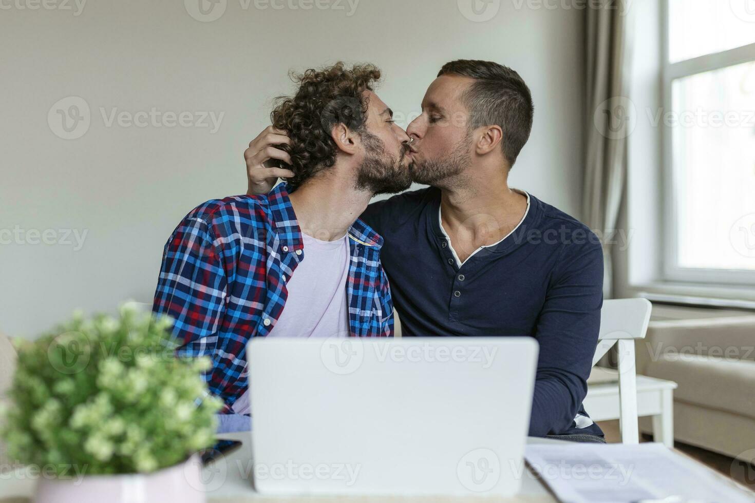 encantador gay Pareja riendo juntos mientras sentado en su vivo habitación a hogar. dos romántico joven masculino amantes teniendo divertido surf el Internet adentro. joven gay Pareja vivo juntos. foto