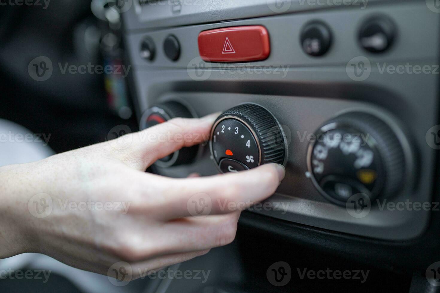 Woman hand turning on car air conditioning system, car air conditioner on off button close up view photo