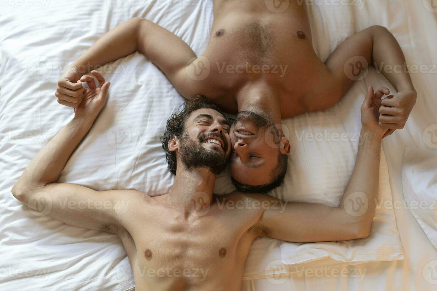 hermoso gay Pareja acostado en cama juntos. romántico joven gay Pareja abrazando cada otro afectuosamente en su dormitorio. dos alegre joven masculino amantes unión afectuosamente a hogar. foto