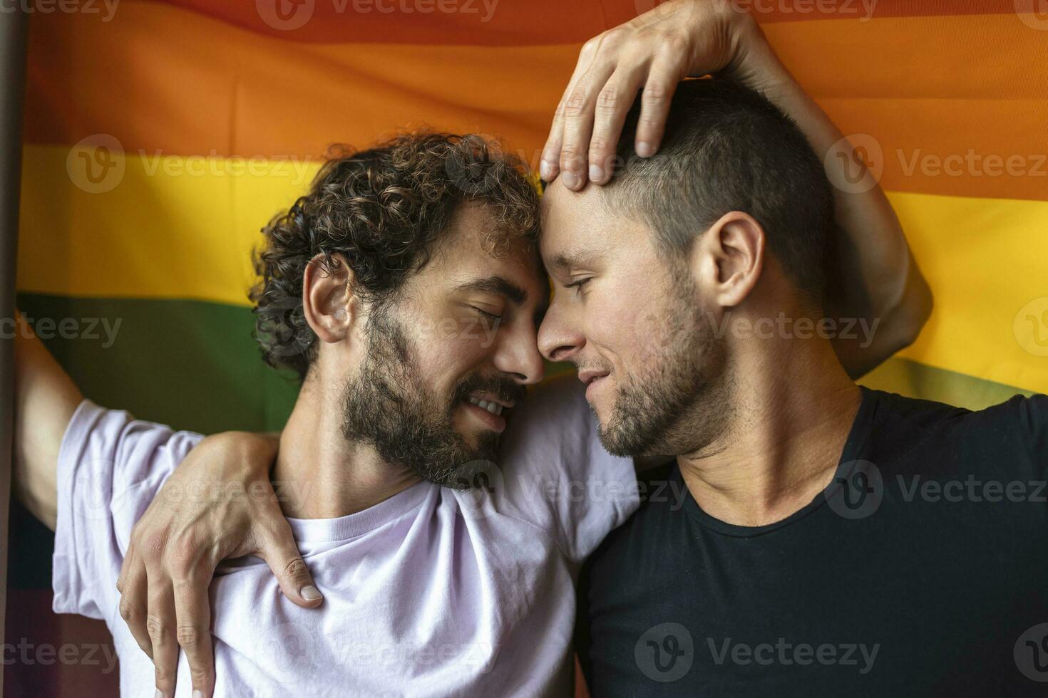 apasionado gay Pareja haciendo fuera con lgbtq bandera en el antecedentes. joven gay Pareja unión afectuosamente adentro. foto