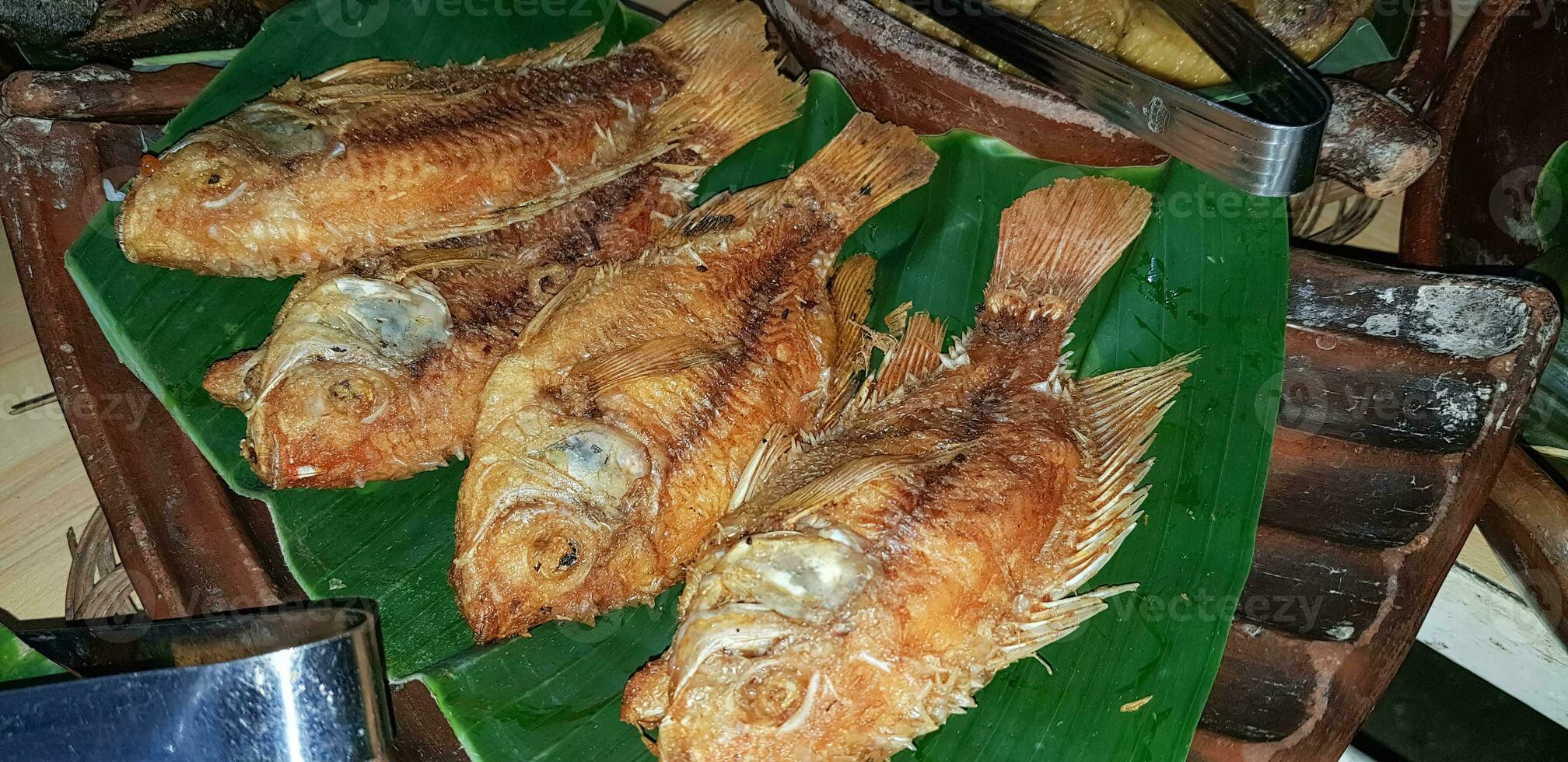 Mariscos plato servido en el mesa y plato desde encima con diferente tipo de plato desde frito pescado barracuda, pargo, atún mandíbulas, y además mezcla de tropical vegetales foto