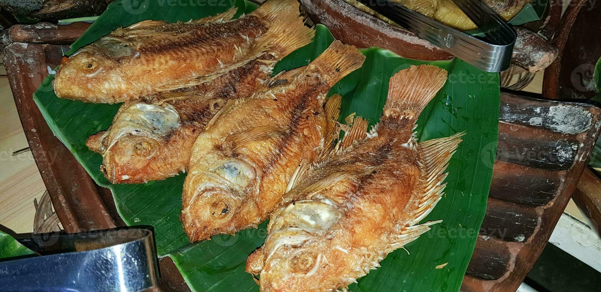 Mariscos plato servido en el mesa y plato desde encima con diferente tipo de plato desde frito pescado barracuda, pargo, atún mandíbulas, y además mezcla de tropical vegetales foto