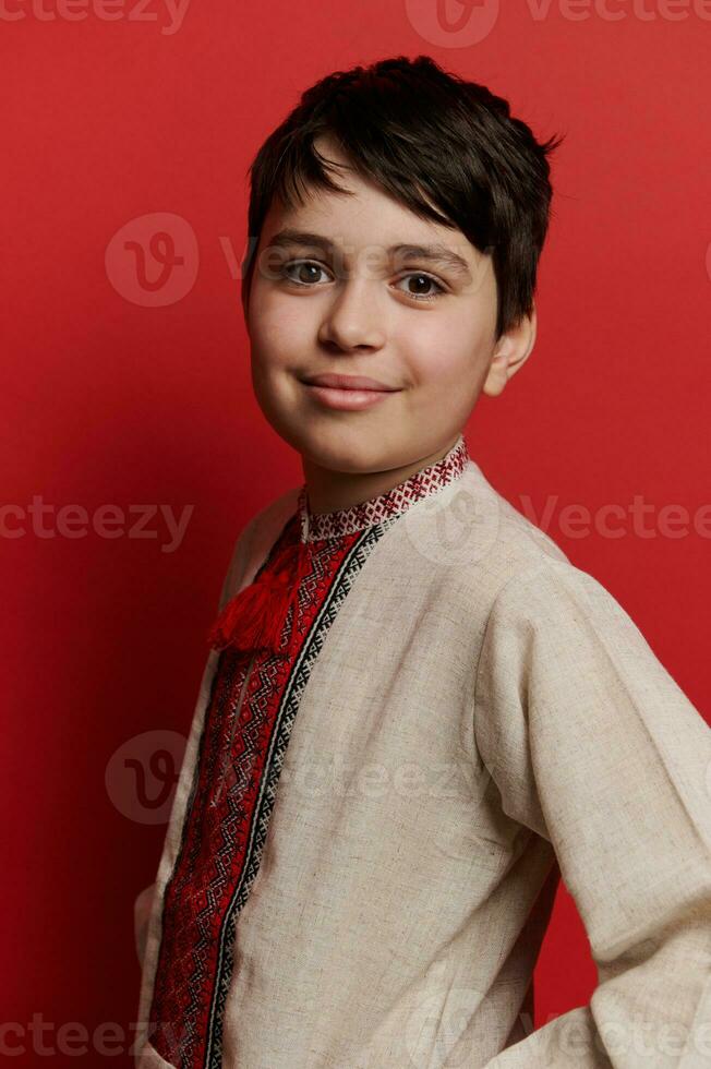 Handsome Caucasian teen boy dressed in traditional ethnic Ukrainian embroidered linen shirt, smiling looking at camera photo