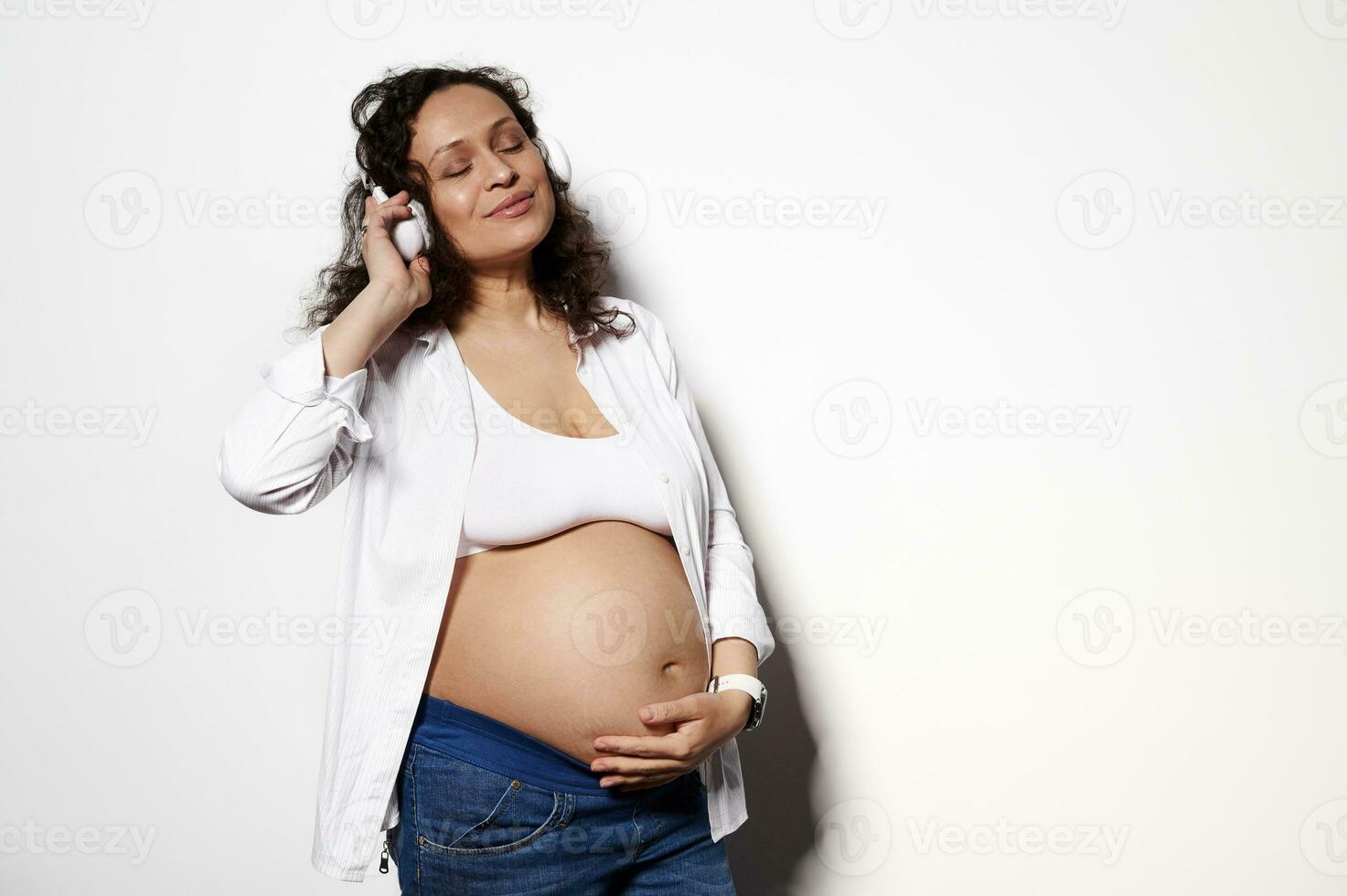 Mid-section of pregnant woman holding headphones at her belly stock photo