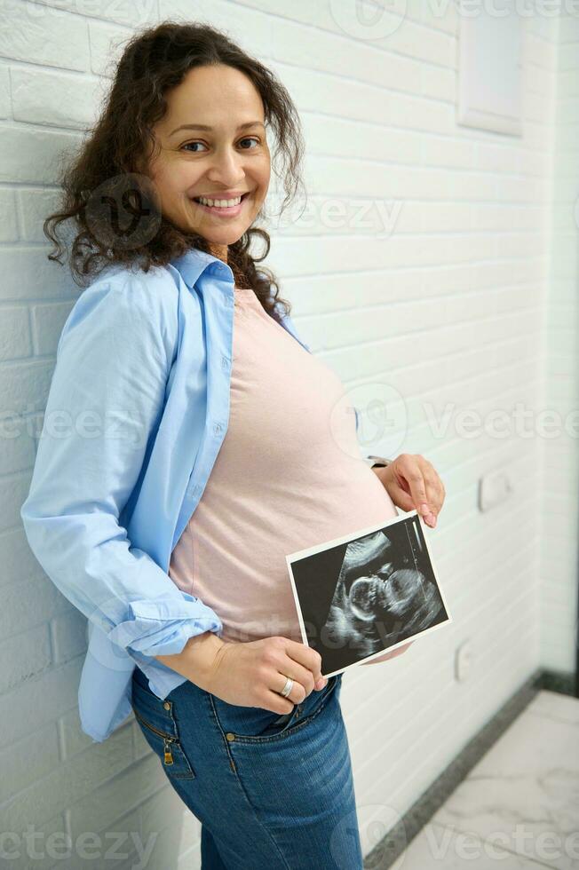 Happy pregnant woman holding ultrasound scan of her baby. Pregnancy. Obstetrics and gynecology concept. Health care photo