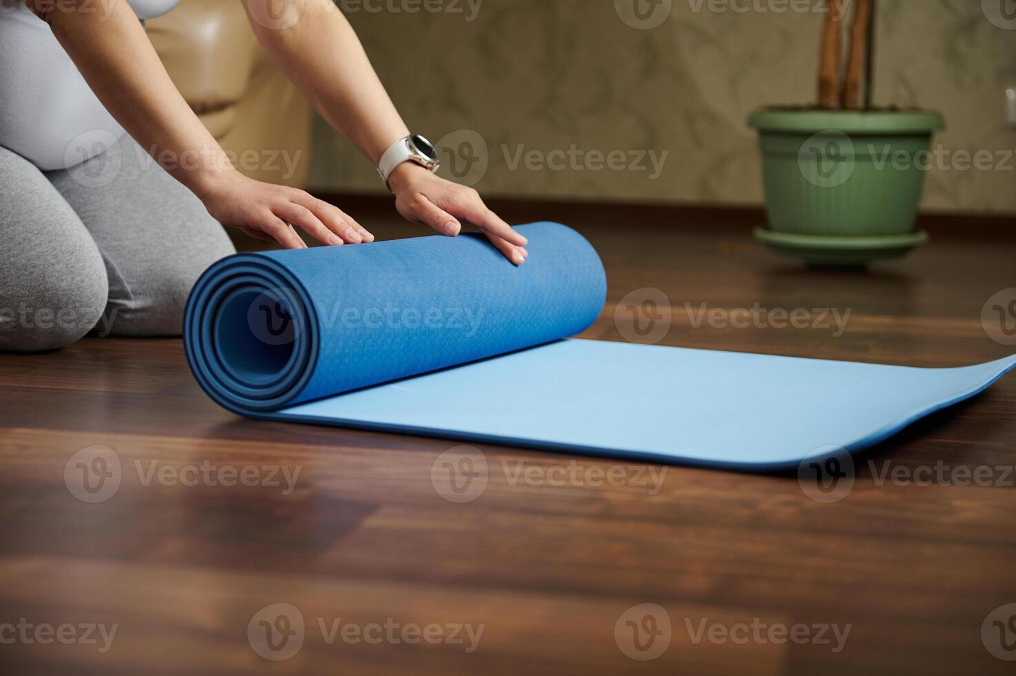 Close-up hands o pregnant woman rolling out a mat while practicing yoga, prenatal stretching, breathing exercises indoor photo