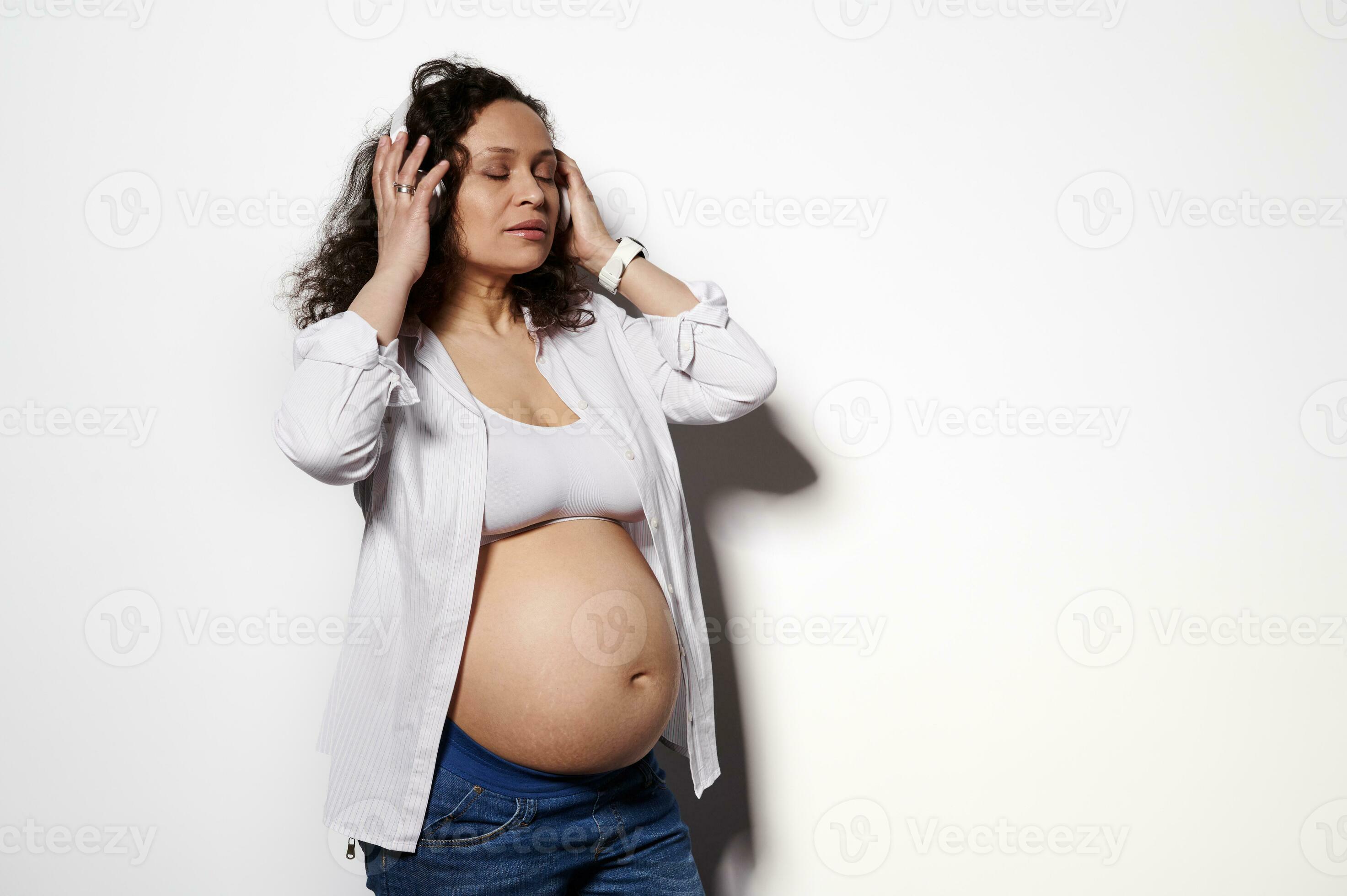 Photo portrait of a delightful pregnant woman showing her belly wearing  wireless headphones isolated on white background 24697018 Stock Photo at  Vecteezy