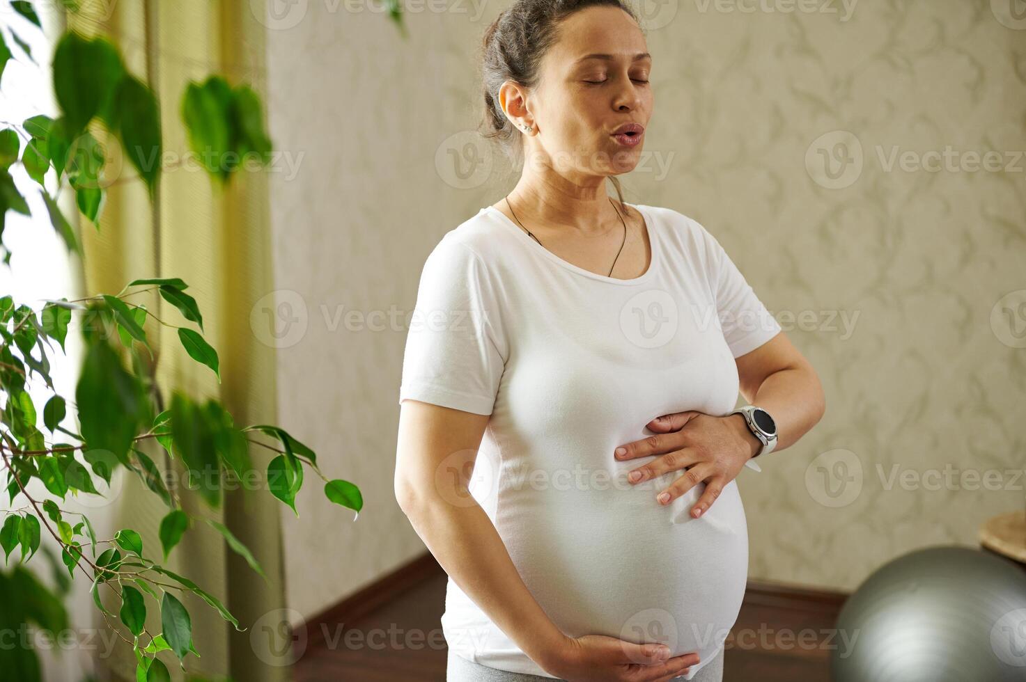 Pregnant woman putting her hands on her big belly, training breathing technique during pregnancy for easy childbirth. photo