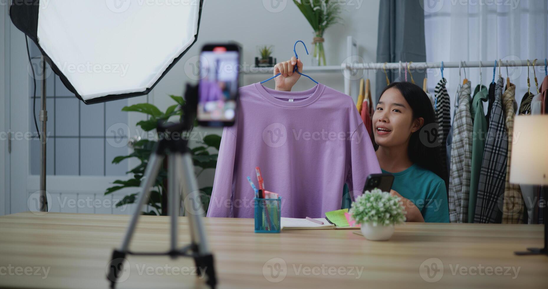 Young Asian female fashion designer using mobile phone live steaming photo