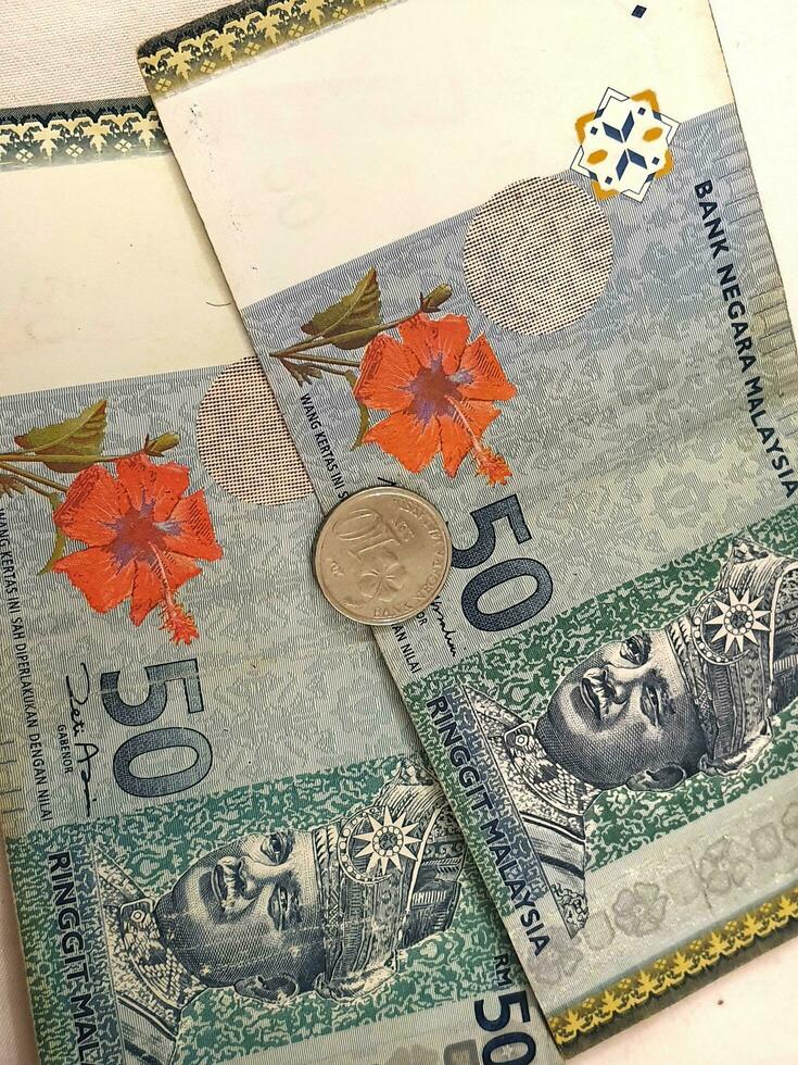 Two 50 ringgit notes, one coin of 10 cents ringgit. photo