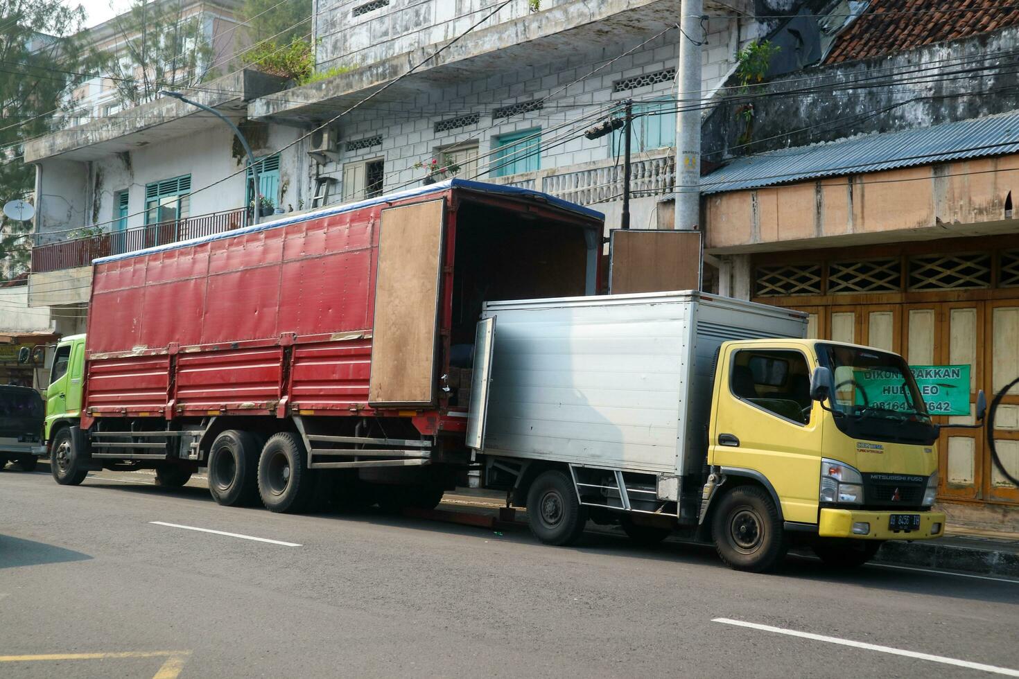 Yogyakarta, Indonesia - March 20 2023 - Shipment package transit to next pickup point. Cargo truck full of package moved to other delivery truck photo
