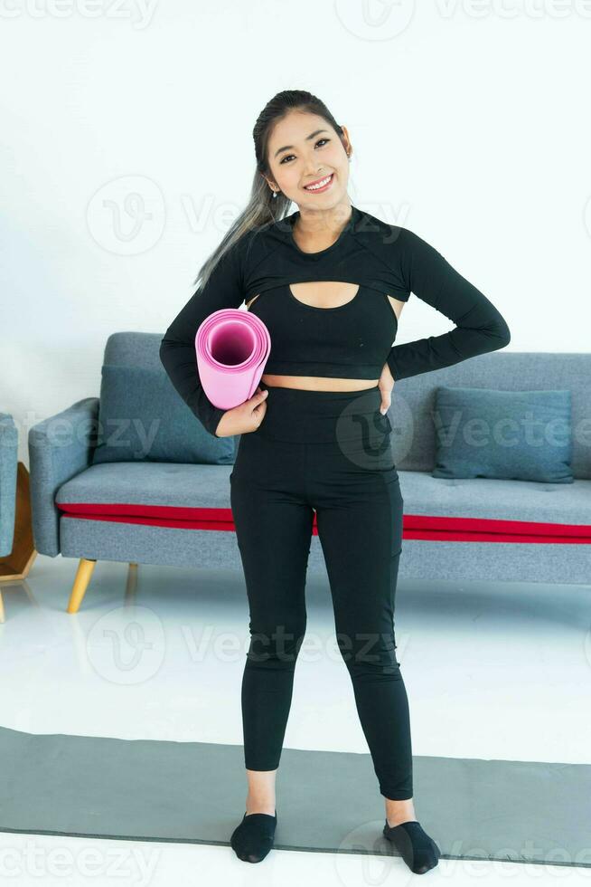 Asian young healthy woman in sportware holding yoga mat at home, Sport girl exercise  in living room at home photo