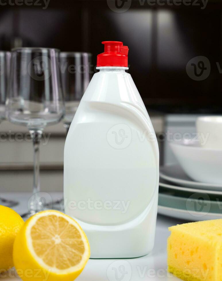 Detergent, lemon, sponge and clean dishes on the table in the kitchen. Cleaning service concept. Close-up. Selective focus. photo