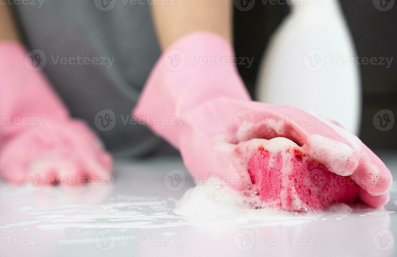 A girl in rubber gloves washes the table with detergent. Concept of spring cleaning. Close-up. Selective focus. photo