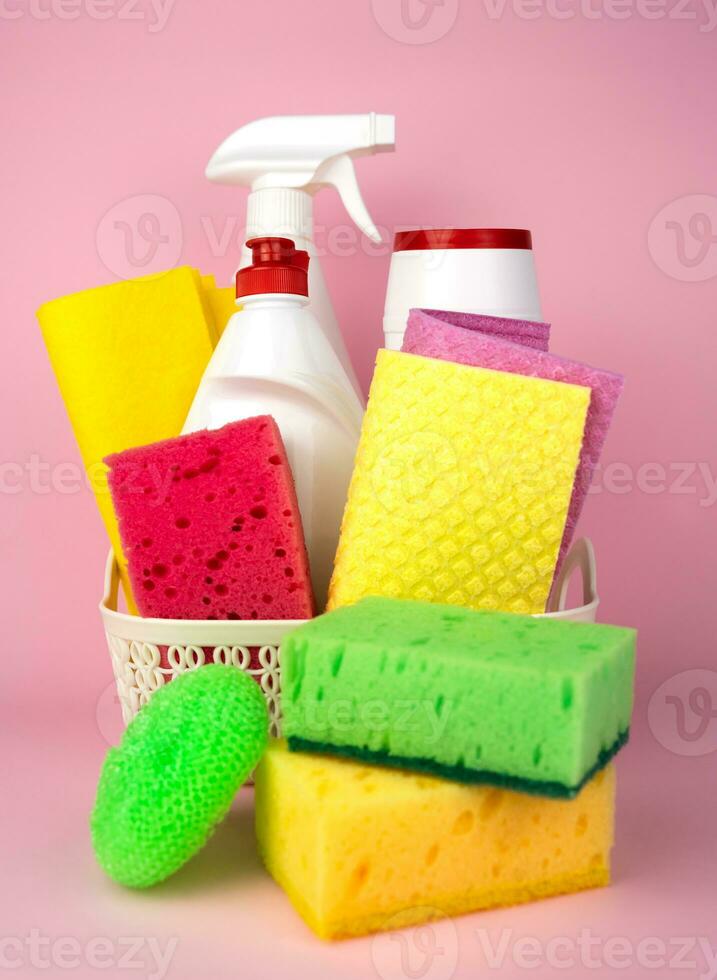 Different cleaning items and supplies on the pink background. Cleaning service concept. Close-up. Selective focus. photo