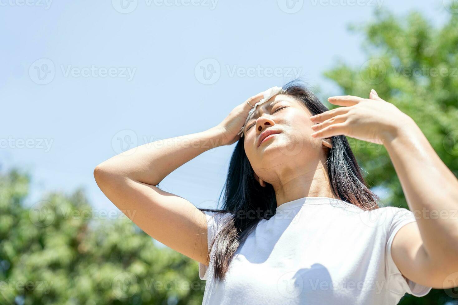 Asian woman drying sweat with a cloth in a warm summer day photo